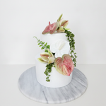 Artificial wedding cake decoration with pink and green faux anthuriums, white orchids and trailing greenery arranged over two tiers. For birthday, event and celebration cakes. Made in Melbourne by Flowers For Ever After, shipping Australia and Worldwide.