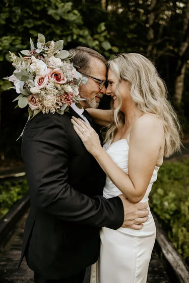 The bride holds a large, elegant bouquet of pink and white flowers with green foliage.  Flowers by Flowers For Ever After